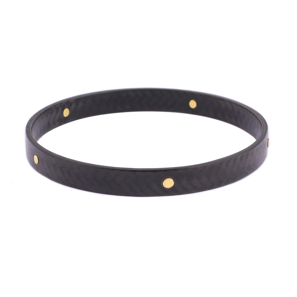 Angled view of Carbon Bangle with Large 18k Yellow Gold Rivets by Diana Hall
